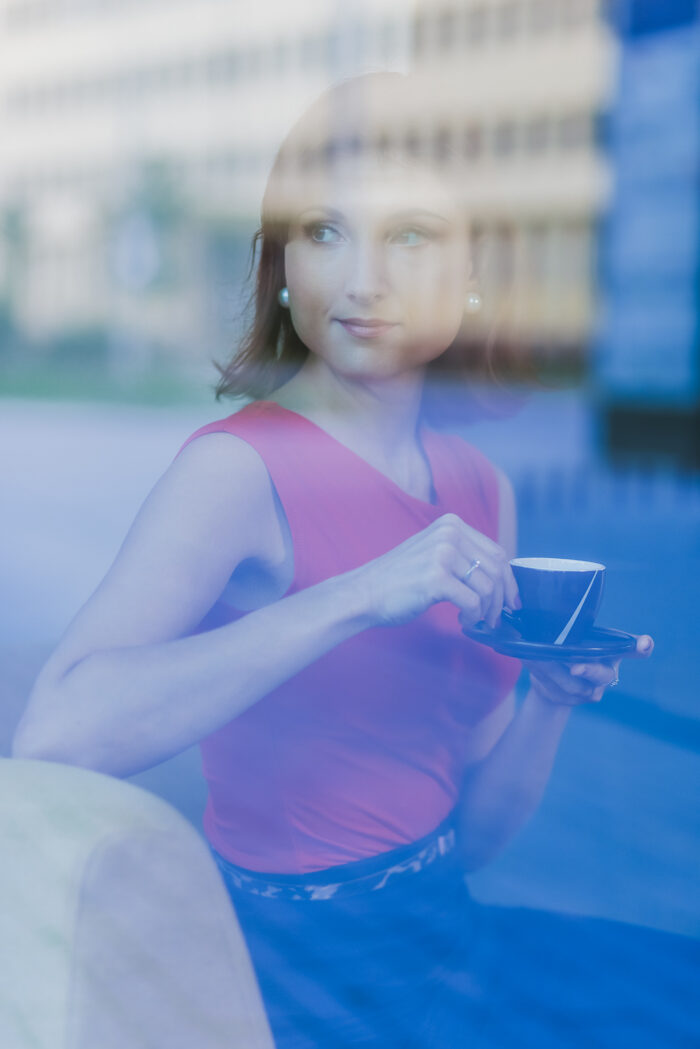 Focení profesní byznys fotografie Business portrét ženy v červených šatech přes skleněnou výlohu