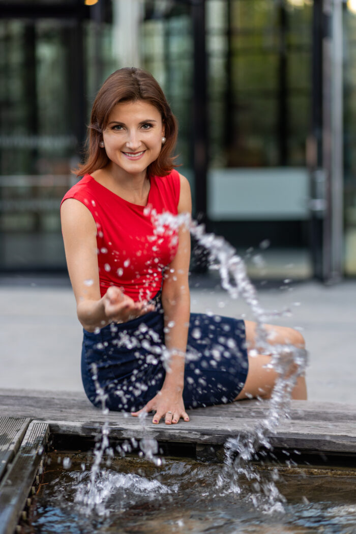 Focení profesní byznys fotografie Profesní portrét ženy v červeném topu u městské fontány